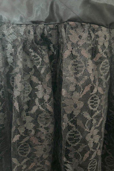 Front detail view of 1960s does 1920s vintage black satin and lace flapper dress costume, small to medium. Showing an area of lace with a red cast to the black.