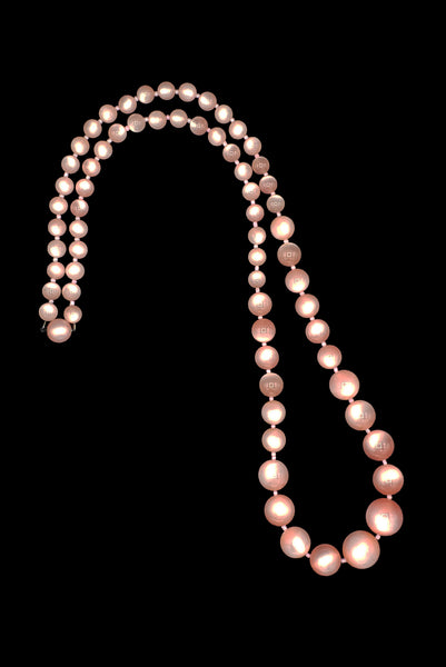 Vertical view of 1960s vintage long pink moonglow Lucite graduated bead necklace.