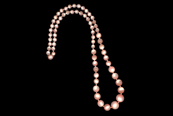 Horizontal view of 1960s vintage long pink moonglow Lucite graduated bead necklace.