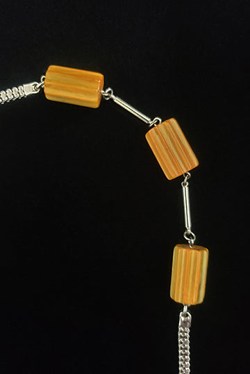 Vertical detail view of 1930s vintage marbled butterscotch Bakelite beads and chrome silver tone chain necklace.