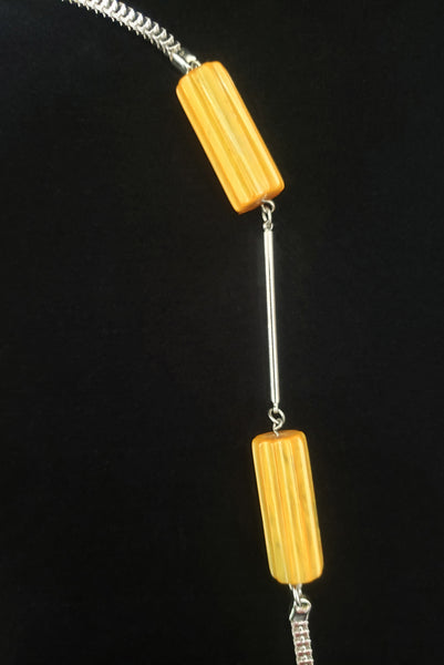 Vertical detail view of 1930s vintage marbled butterscotch Bakelite beads and chrome silver tone chain necklace.