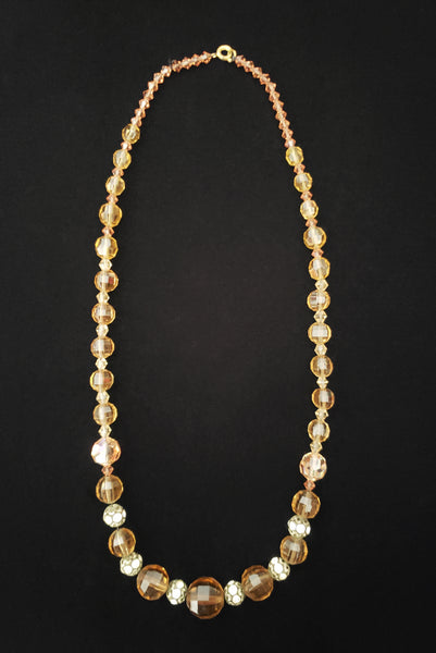 Vertical top view of 1960s vintage smokey topaz mauve graduated crystal bead and silver tone rhinestone spacer long necklace. Showing the bicone beads that were added by the clasp.