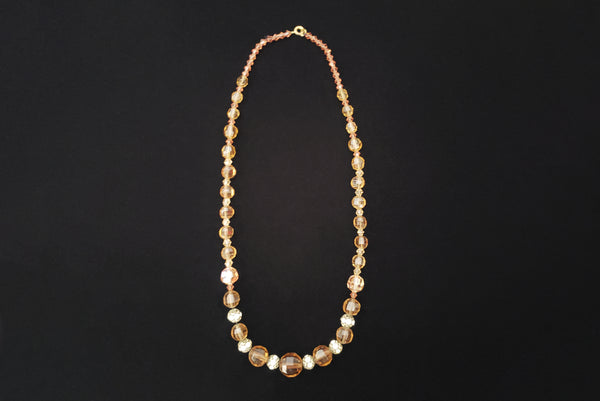 Horizontal top view of 1960s vintage smokey topaz mauve graduated crystal bead and silver tone rhinestone spacer long necklace. Showing the bicone beads that were added by the clasp.