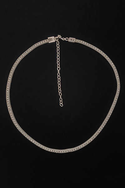 Vertical top view of 1960s vintage adjustable silver tone metal mesh and rhinestone chain belt with floral hook, size medium to large.