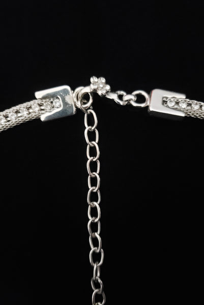 Detail view of 1960s vintage adjustable silver tone metal mesh and rhinestone chain belt with floral hook, size medium to large. Showing the adjustable chain and silver tone rhinestone floral hook closure.