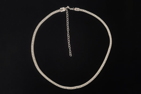 Horizontal top view of 1960s vintage adjustable silver tone metal mesh and rhinestone chain belt with floral hook, size medium to large.