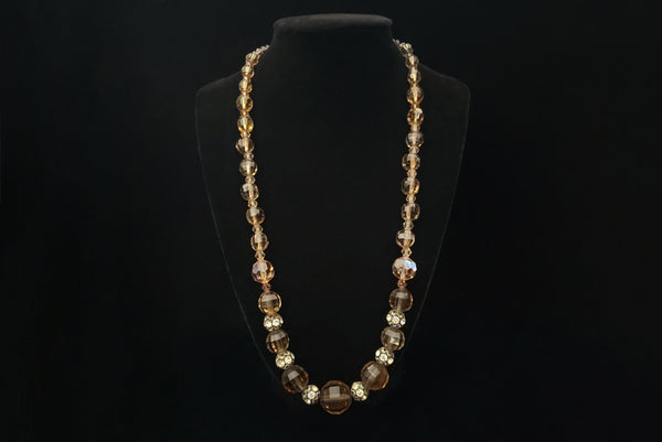 Horizontal front view of 1960s vintage smokey topaz mauve graduated crystal bead and silver tone rhinestone spacer long necklace.