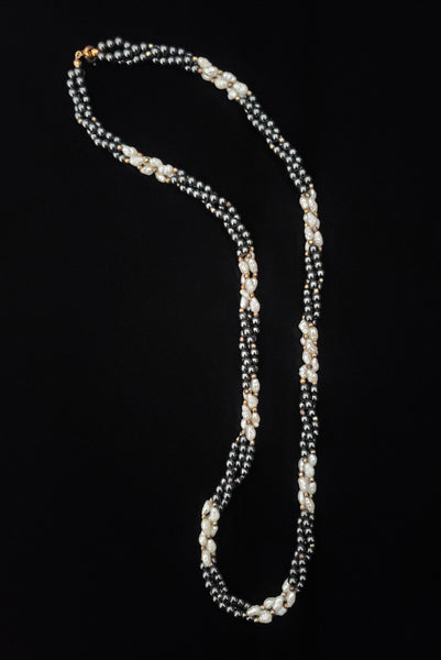 Vertical view of 1980s vintage white freshwater pearl, gray hematite, and gold tone beaded twisted triple strand long necklace.