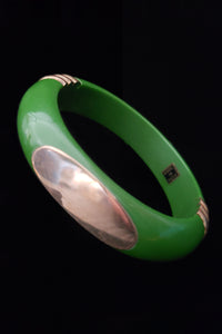 Vertical perspective view of 1970s vintage green plastic and brass bangle bracelet, made in India.