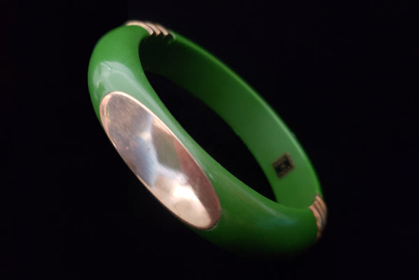 Horizontal perspective view of 1970s vintage green plastic and brass bangle bracelet, made in India.
