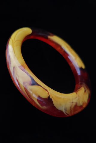 Vertical perspective view of 1960s vintage translucent orange and mustard marbled artisan asymmetrical bangle bracelet.