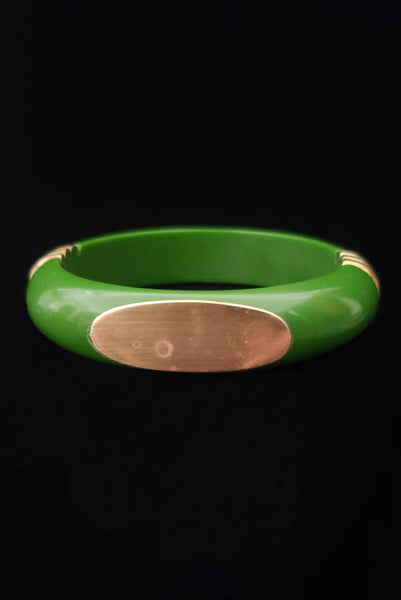 Vertical front view of 1970s vintage green plastic and brass bangle bracelet, made in India. Showing some spots on the brass plate.