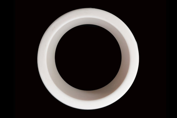 Horizontal top view of 1960s vintage white Lucite plastic sliced bangle bracelet with raised gray marbled dots.