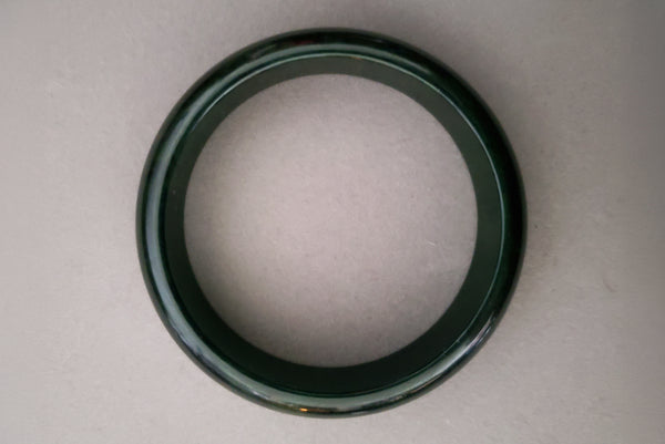 Horizontal top view of 1930s vintage dark blue moon, marbled green and blue Bakelite bangle bracelet.