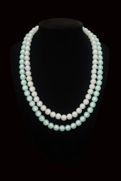 Vertical view of 1960s vintage double strand moonglow Lucite two tone blue adjustable necklace. Showing the necklace on a display.