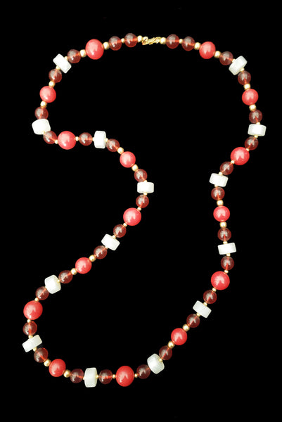 Horizontal view of 1960s vintage red & white Lucite plastic beaded long necklace with gold tone spacers by Monet.