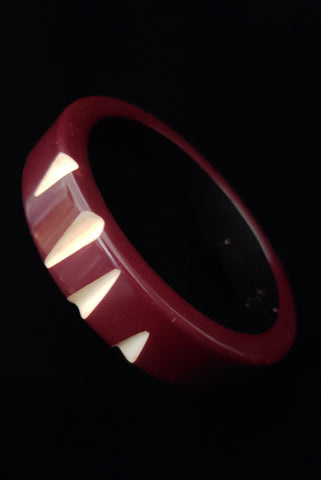 Vertical perspective view of 1940s vintage red purple resin washed  sliced cream cut through carved Bakelite bangle bracelet.