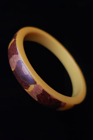 Vertical perspective view of 1940s vintage egg yolk brown wood grain laminated Bakelite bangle bracelet.