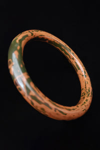 Vertical perspective view of 1930s vintage dark green and peanut butter brown camo Iro Urushi layered lacquer tube bangle bracelet.
