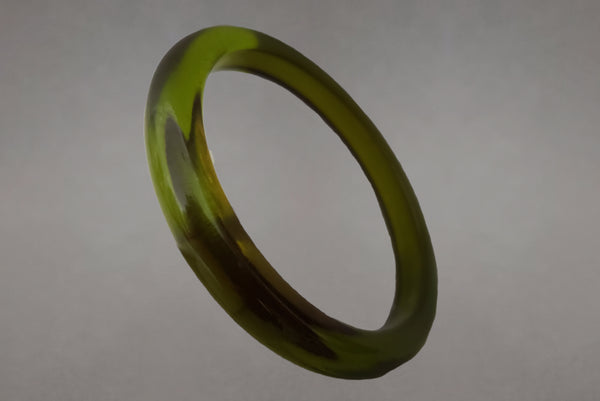 Horizontal perspective view of 1930s vintage prystal translucent green domed plastic Bakelite bangle bracelet.