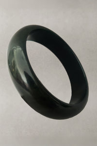 Vertical perspective view of 1930s vintage dark blue moon, marbled green and blue Bakelite bangle bracelet.