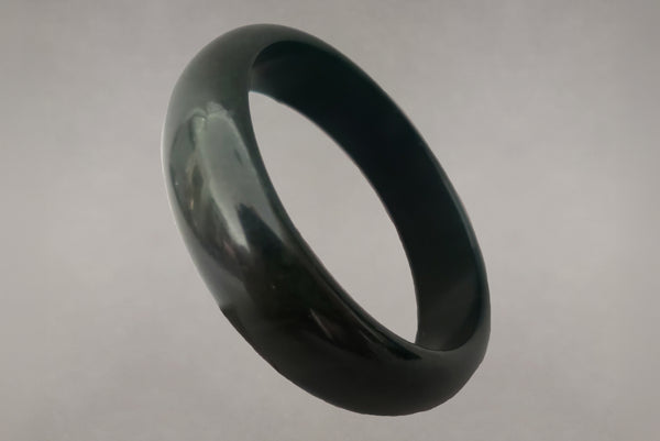 Horizontal perspective view of 1930s vintage dark blue moon, marbled green and blue Bakelite bangle bracelet.