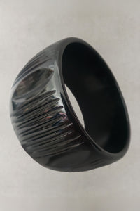 Vertical perspective view of 1930s vintage wide black carved Bakelite statement bangle bracelet.