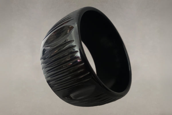 Horizontal perspective view of 1930s vintage wide black carved Bakelite statement bangle bracelet.