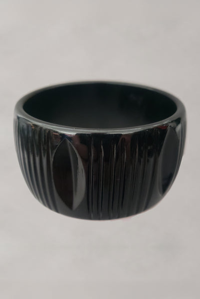 Vertical front view of 1930s vintage wide black carved Bakelite statement bangle bracelet.