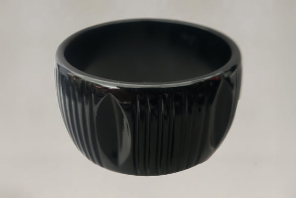 Horizontal front view of 1930s vintage wide black carved Bakelite statement bangle bracelet.