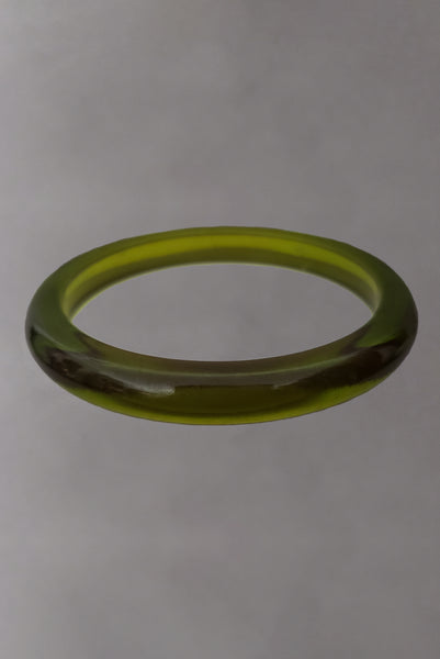 Vertical front view of 1930s vintage prystal translucent green domed plastic Bakelite bangle bracelet.