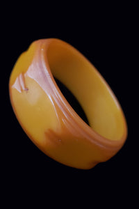 Vertical perspective view of 1930s vintage link carved egg yolk mustard Bakelite bangle bracelet.