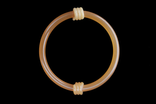 Horizontal top view of 1960s vintage translucent mustard yellow plastic tube bangle bracelet with wrapped phone cord detailing.