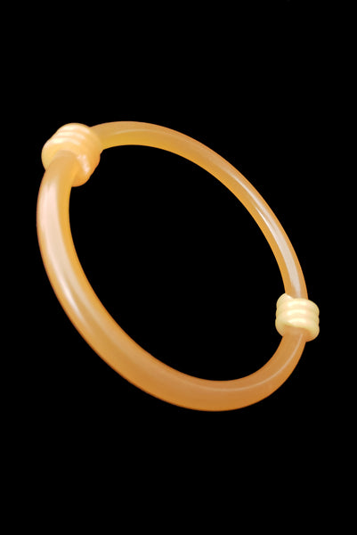 Vertical perspective view of 1960s vintage translucent mustard yellow plastic tube bangle bracelet with wrapped phone cord detailing.
