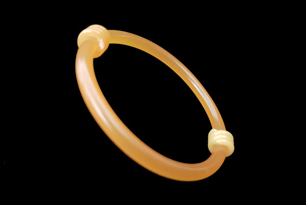 Horizontal perspective view of 1960s vintage translucent mustard yellow plastic tube bangle bracelet with wrapped phone cord detailing.