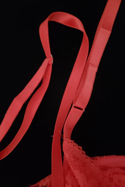 Strap detail view of 1950s vintage crimson red nylon and lace full slip by Van Raalte, small to medium. Showing a few marks on the adjustable red satin ribbon straps.