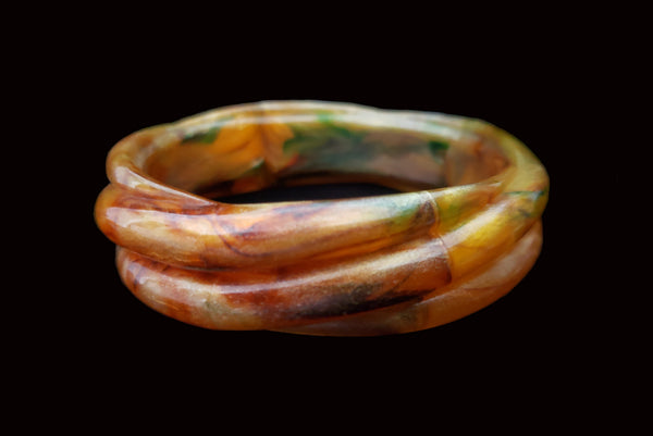 Horizontal front view of 1980s vintage pearly green and brown molded plastic bangle bracelet.