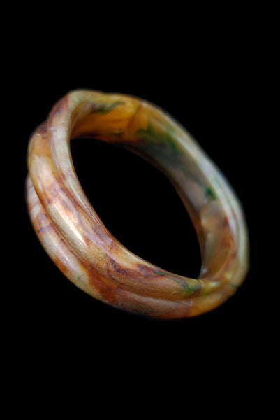 Vertical perspective view of 1980s vintage pearly green and brown molded plastic bangle bracelet.