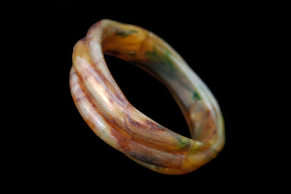 Horizontal perspective view of 1980s vintage pearly green and brown molded plastic bangle bracelet.