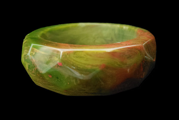 Horizontal front view of 1940s vintage chunky green and red marbled facet carved Bakelite bangle bracelet.