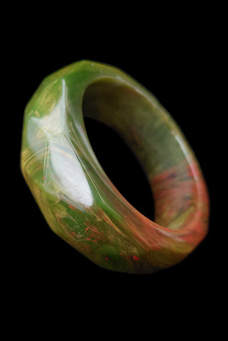 Vertical perspective view of 1940s vintage chunky green and red marbled facet carved Bakelite bangle bracelet.