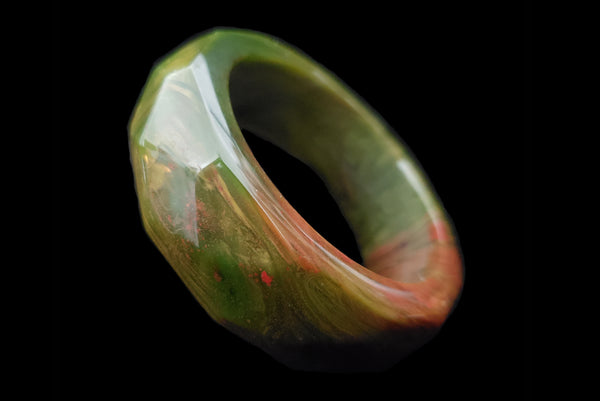 Horizontal perspective view of 1940s vintage chunky green and red marbled facet carved Bakelite bangle bracelet.