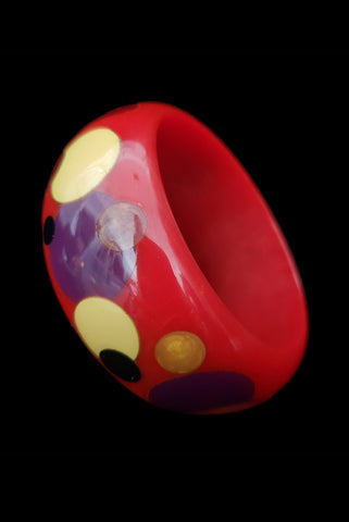 Vertical perspective view of rare vintage black, purple, orange, pink, and cream corn confetti dot red Bakelite bangle bracelet.