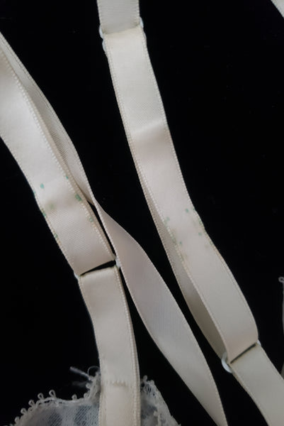 Strap detail view of 1950s vintage white sheer lace sweetheart neckline full slip by Vanity Fair, small to medium. Showing some discoloration to the satin ribbon.
