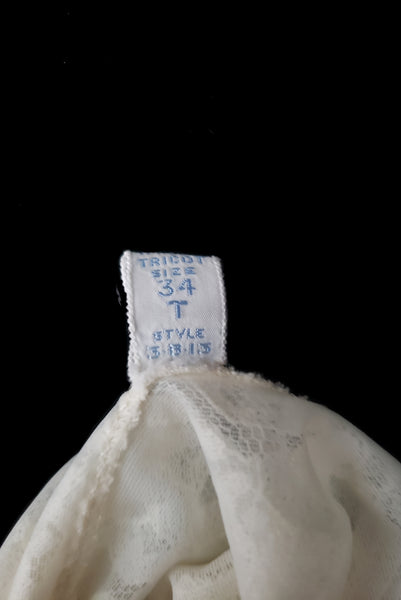 Interior detail view of 1950s vintage white sheer lace sweetheart neckline full slip by Vanity Fair, small to medium. Showing the size 34 tall tag.