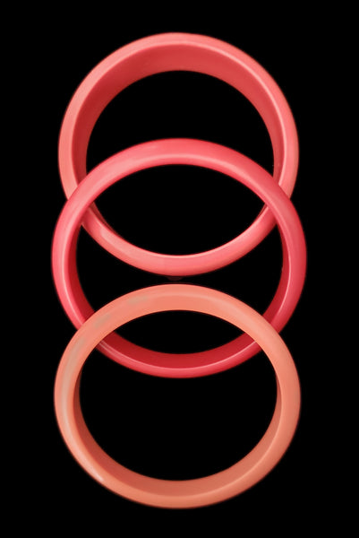 Vertical top view of 1980s vintage coral pink plastic bangle bracelet set of three (3).