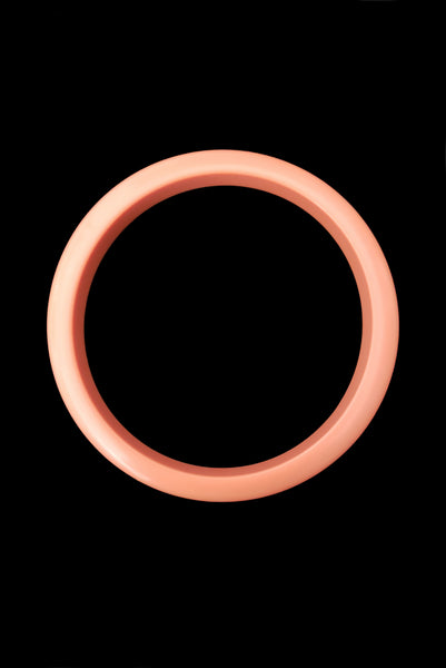Vertical top view of 1980s vintage coral pink plastic bangle bracelet set of three (3). Showing the lightest bangle on its own.