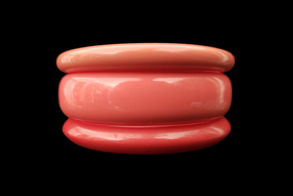 Horizontal front view of 1980s vintage coral pink plastic bangle bracelet set of three (3).
