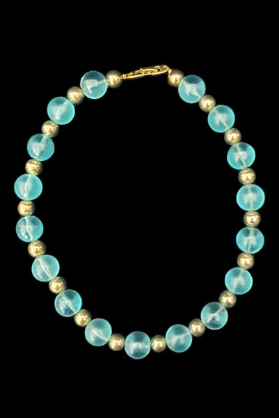 Vertical view of 1980s vintage transparent aqua blue Lucite plastic and gold tone metal large bead necklace by Napier.