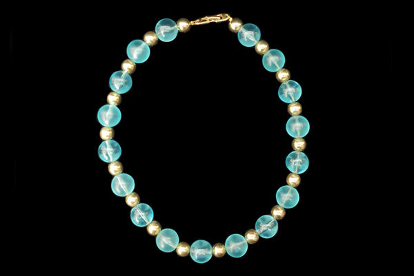 Horizontal view of 1980s vintage transparent aqua blue Lucite plastic and gold tone metal large bead necklace by Napier.